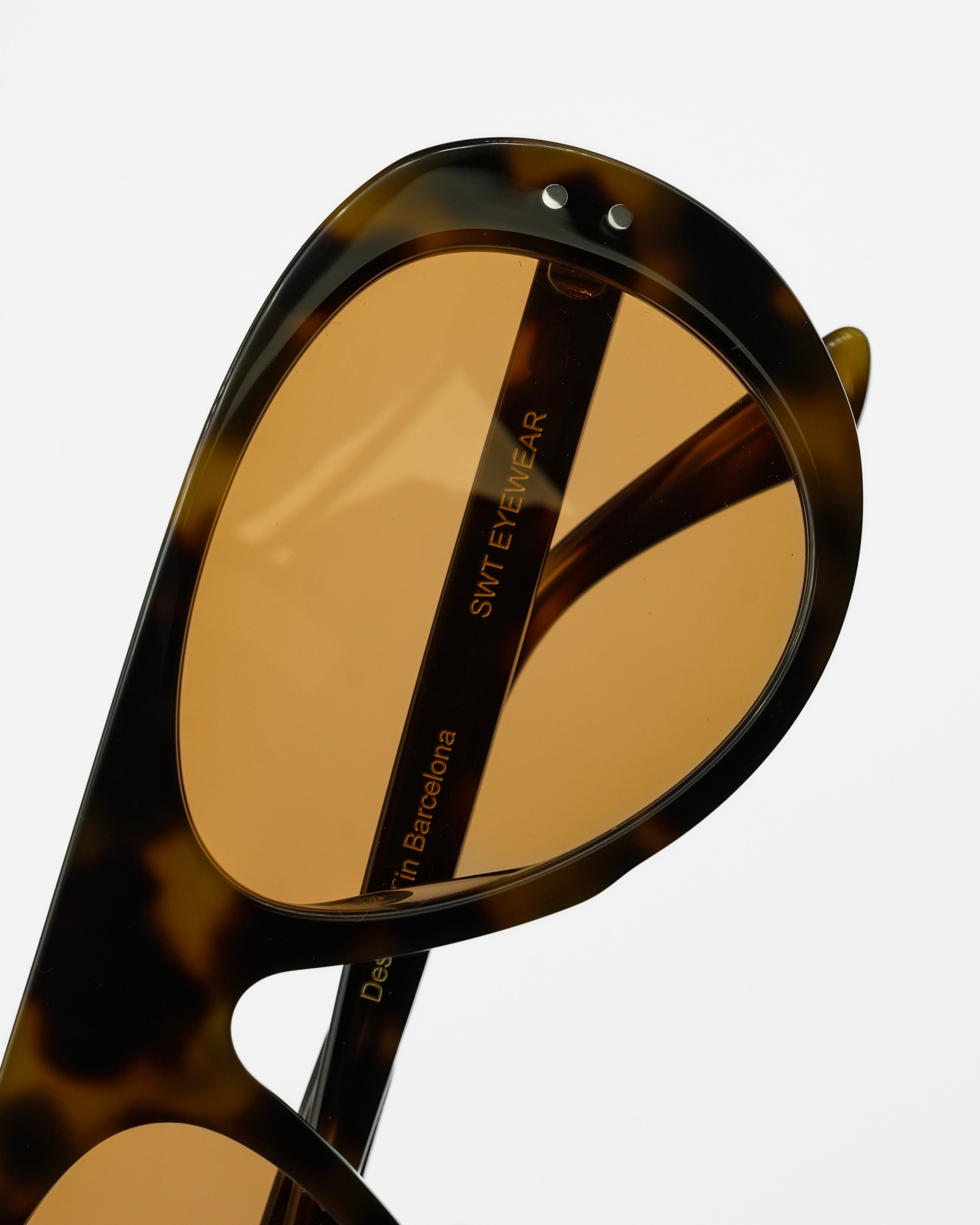 Dragon sunglasses by SWT, close-up of warm amber lens and acetate rivet detail